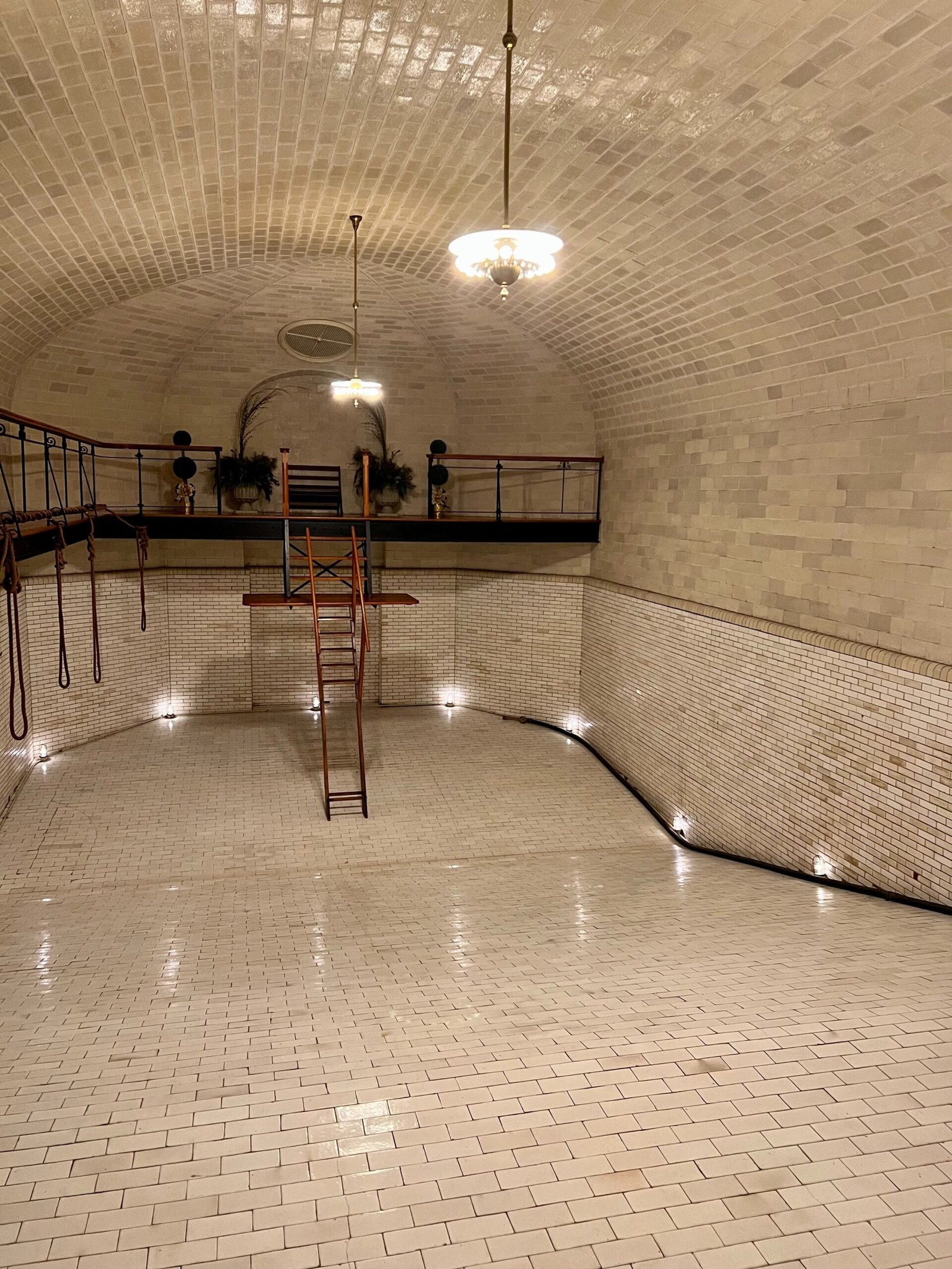 a white tiled room with a ladder and lights